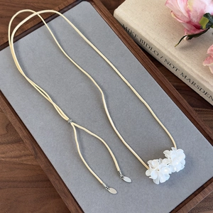 Vue détaillée du pendentif floral blanc sur un tour de cou en daim beige doux