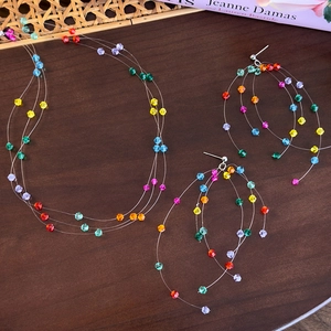 Set collana e orecchini di perline colorate su sfondo di superficie in legno rustico