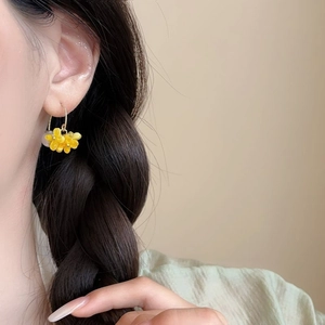 Eleganti orecchini a fiore di osmanto con ganci dorati e nappe di perle su una modella