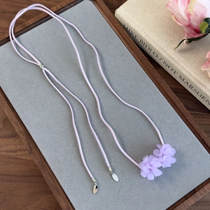Gros plan du choker lariat avec fleurs en résine lavande sur cordon en daim rose