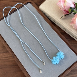 Détail du ras-du-cou bleu clair à fleurs avec longs liens en velours et pendentifs