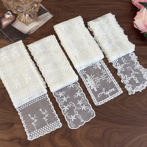Detail view of four unique white lace ribbons with mesh embroidery on dark wood surface