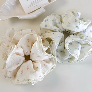 Close-up of floral scrunchies in pink and blue chiffon fabric with ribbed texture