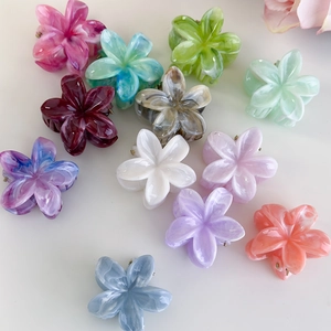 Detailed view of colorful marble textured plumeria flower hair claws in diverse shades