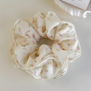 Detail of floral chiffon scrunchie with pink flowers and wavy edge on a ceramic tray