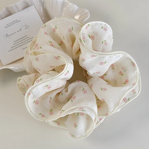 Detailed close-up of a floral scrunchie on a decorative white shell tray