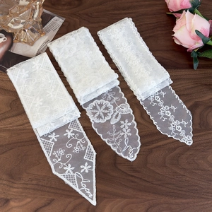 Detail shot of white lace ribbons with floral embroidery and Love lettering on wood