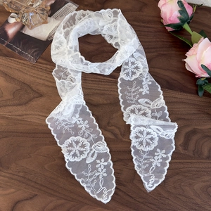 Close-up of white lace scarf with floral mesh patterns on vintage wooden surface