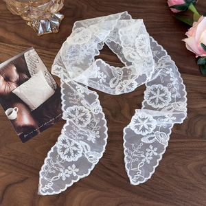 Close-up of white lace scarf showing intricate floral embroidery and scalloped edges