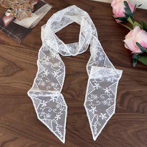 Close-up of white lace scarf with floral embroidery and字母 embroidery on a desk