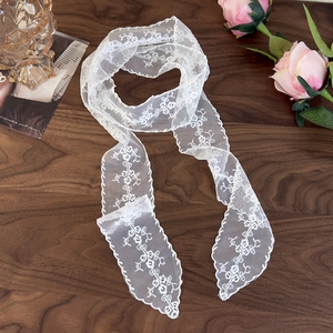 Detail of white floral lace scarf with embroidery and scalloped edges on a wooden table