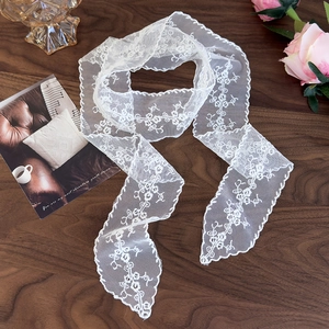 Macro shot of white lace scarf with floral embroidery on dark wood surface