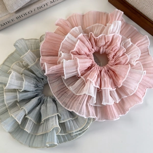 Detailed view of layered ruffle edge hair scrunchies with pleated chiffon texture