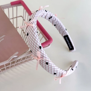 Détail du serre-tête en éponge à carreaux roses avec nœuds et étiquette faite main