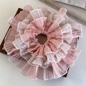 Detail of multi-layered pink and white ruffled chiffon scrunchie on a wooden tray