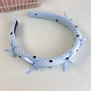 Détail d'un serre-tête doux à carreaux bleus avec motifs cœurs et nœuds en soie