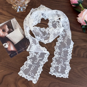 Detail of white lace scarf with floral embroidery on a rustic wooden table