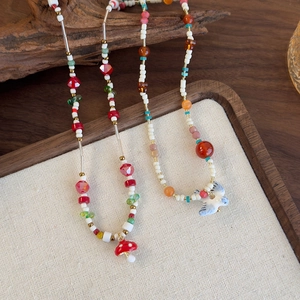 Collier de perles en résine colorées avec pendentifs champignon et oiseau sur bois rustique