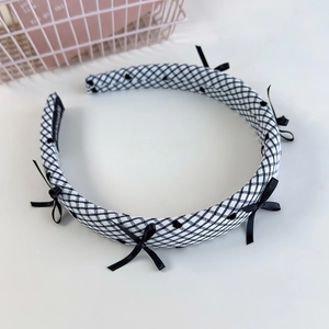 Détail du serre-tête à carreaux noir et blanc orné de nœuds en soie et tissu texturé
