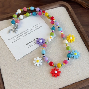 Close-up of a colorful beaded daisy necklace with vibrant floral pendants on linen