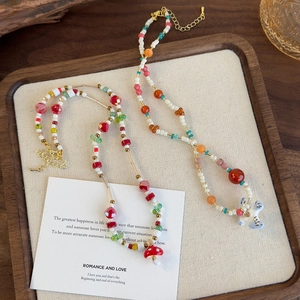 Colliers de perles colorées avec pendentifs champignon et hirondelle sur un plateau