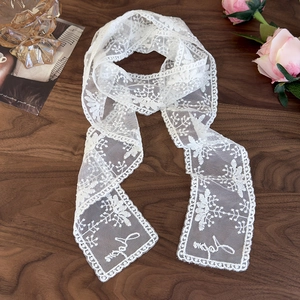Close-up of white lace floral ribbon with Japan embroidery on a vintage wood desk