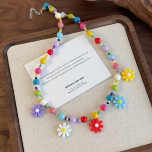 Detail shot of colorful beaded daisy necklace with five resin flower pendants on tray