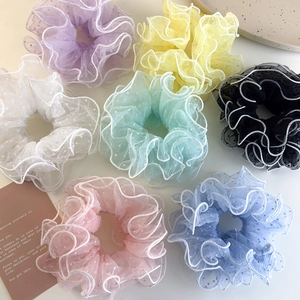 Macro detail of seven colorful mesh polka dot scrunchies with white scalloped edges