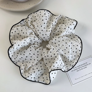 Dettaglio di un grande elastico in seersucker crema con motivo a stelle nere e bordo cucito