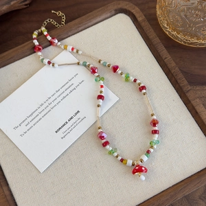 Gros plan d'un collier de perles colorées avec pendentif champignon rouge sur plateau