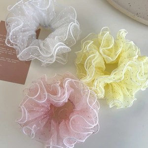 Detailed view of three mesh hair scrunchies with polka dots in white, yellow, and pink
