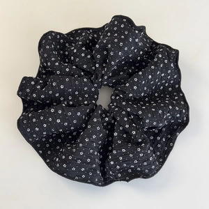 Dettaglio di elastico scrunchie nero in seersucker con stampa di stelle bianche e texture