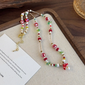 Détail de perles en résine colorées avec pendentif champignon rouge et fermoir doré