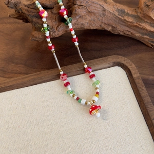 Vue détaillée d'un collier de perles fait main avec pendentif champignon sur bois ancien