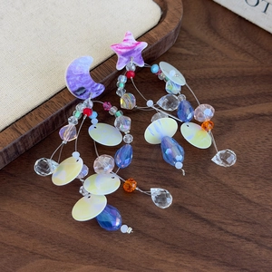 Detail shot of asymmetric long earrings with purple moon and star and colorful crystal beads