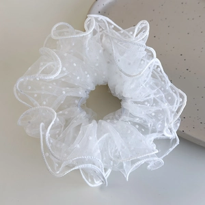 Close-up of white mesh hair scrunchie with polka dots and pleated translucent texture
