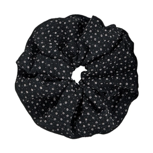 Grande elastico scrunchie nero in seersucker con stelle bianche su sfondo bianco semplice