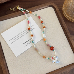 Détail du collier de perles colorées avec pendentif oiseau posé sur un plateau en bois