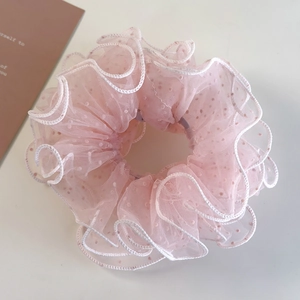 Detail of pink mesh polka dot scrunchie with white wavy edges and pleated texture