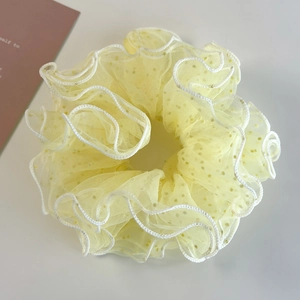 Detail of yellow tulle mesh scrunchie with white wavy edges and golden polka dots decoration