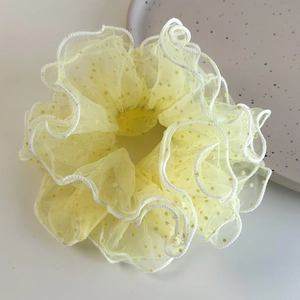 Detailed texture of yellow mesh scrunchie with polka dots and white wavy scalloped edges