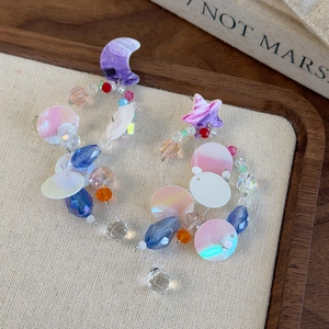 Star and moon long beaded crystal earrings with colorful charms on a linen tray