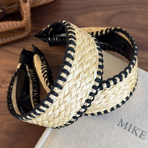 Bohemian woven straw headband with black stitched edges on vintage book background