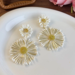 Detail of colorful daisy earrings with white petals and gold core in a ceramic plate