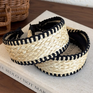 Detailed macro view of woven raffia headband with black cotton stitching and fabric lining