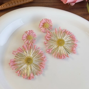 Detail of pink floral earrings with golden pistils on a white ceramic plate