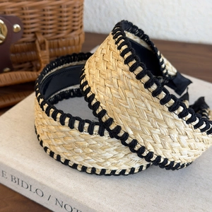 Detail showing natural straw weave texture and black contrast stitching on wide headbands