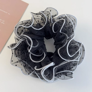 Close-up of black mesh scrunchie with white wavy edges and polka dots for bun hair