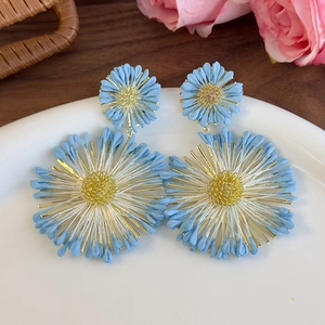 Close-up of blue floral drop earrings with silk petals and gold woven centers
