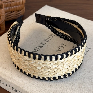 Close-up of bohemian woven straw headband with black stitched edges on art book